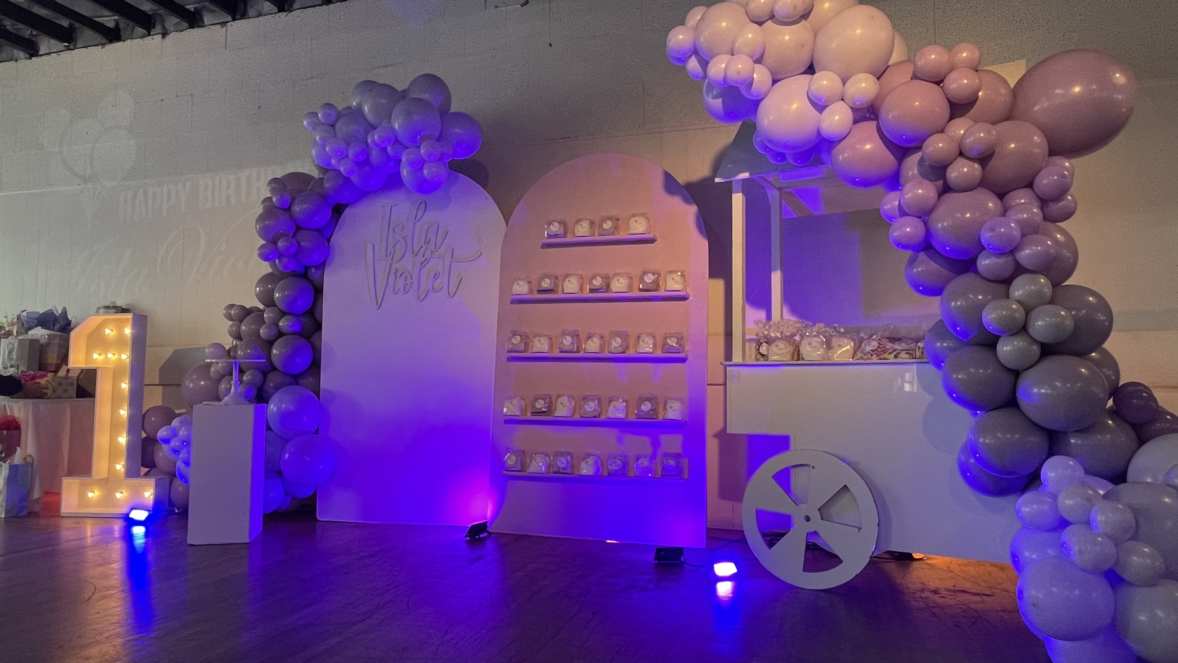 First birthday backdrop with arched display, marquee number, and pastel balloon installation