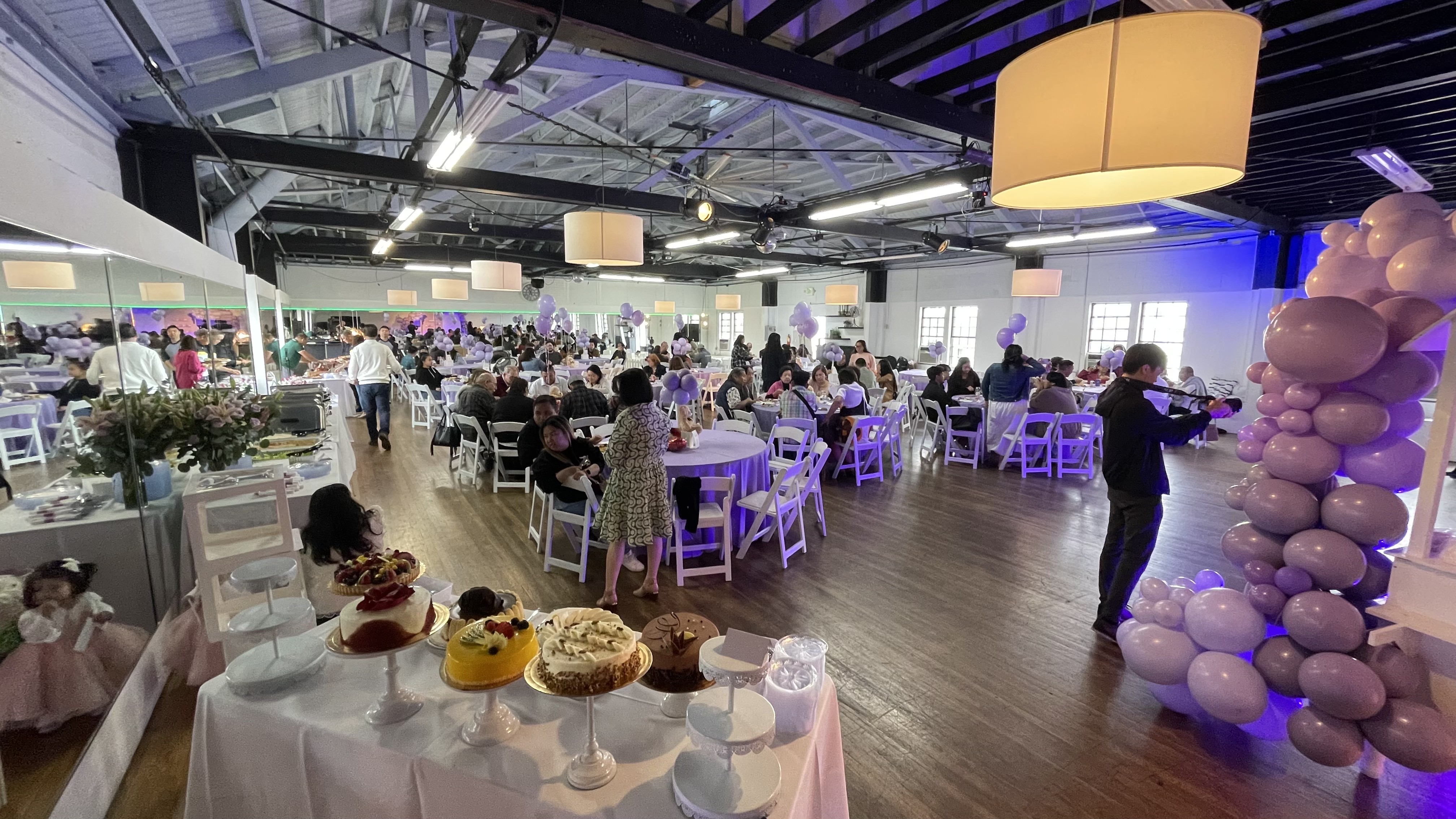 Wide view of the ballroom set for a banquet with purple uplighting and round tables