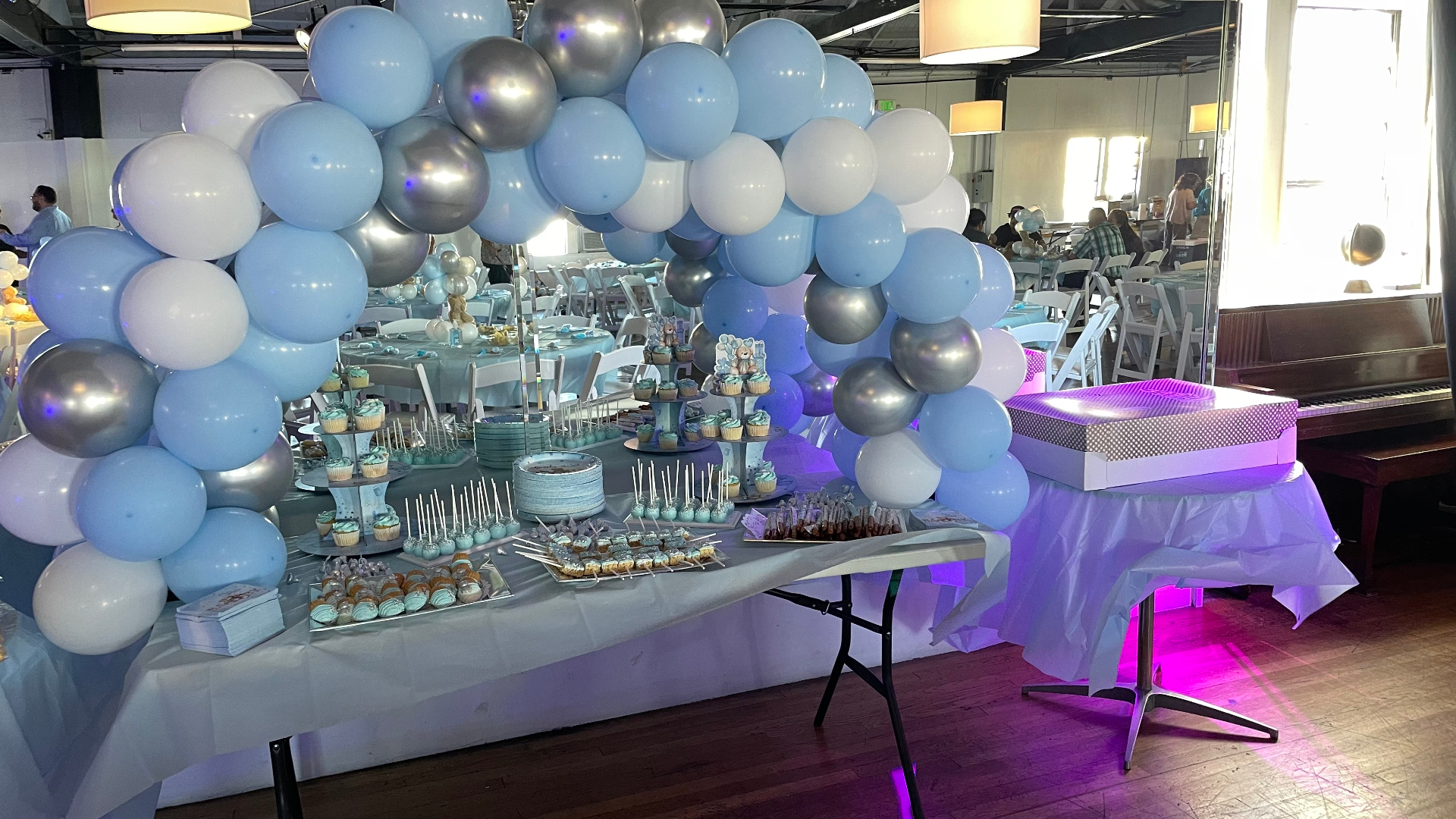 Dessert table framed by a pale blue and silver balloon arch