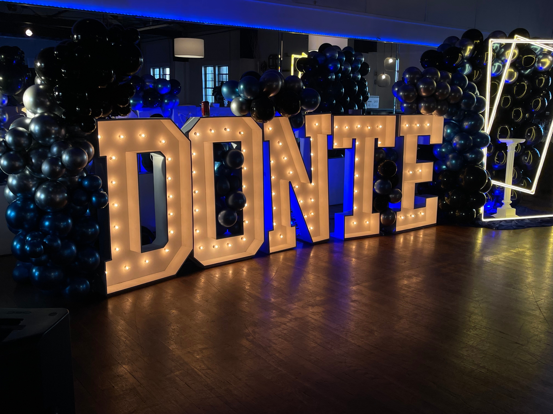 Event with illuminated marquee letters and black balloon installation