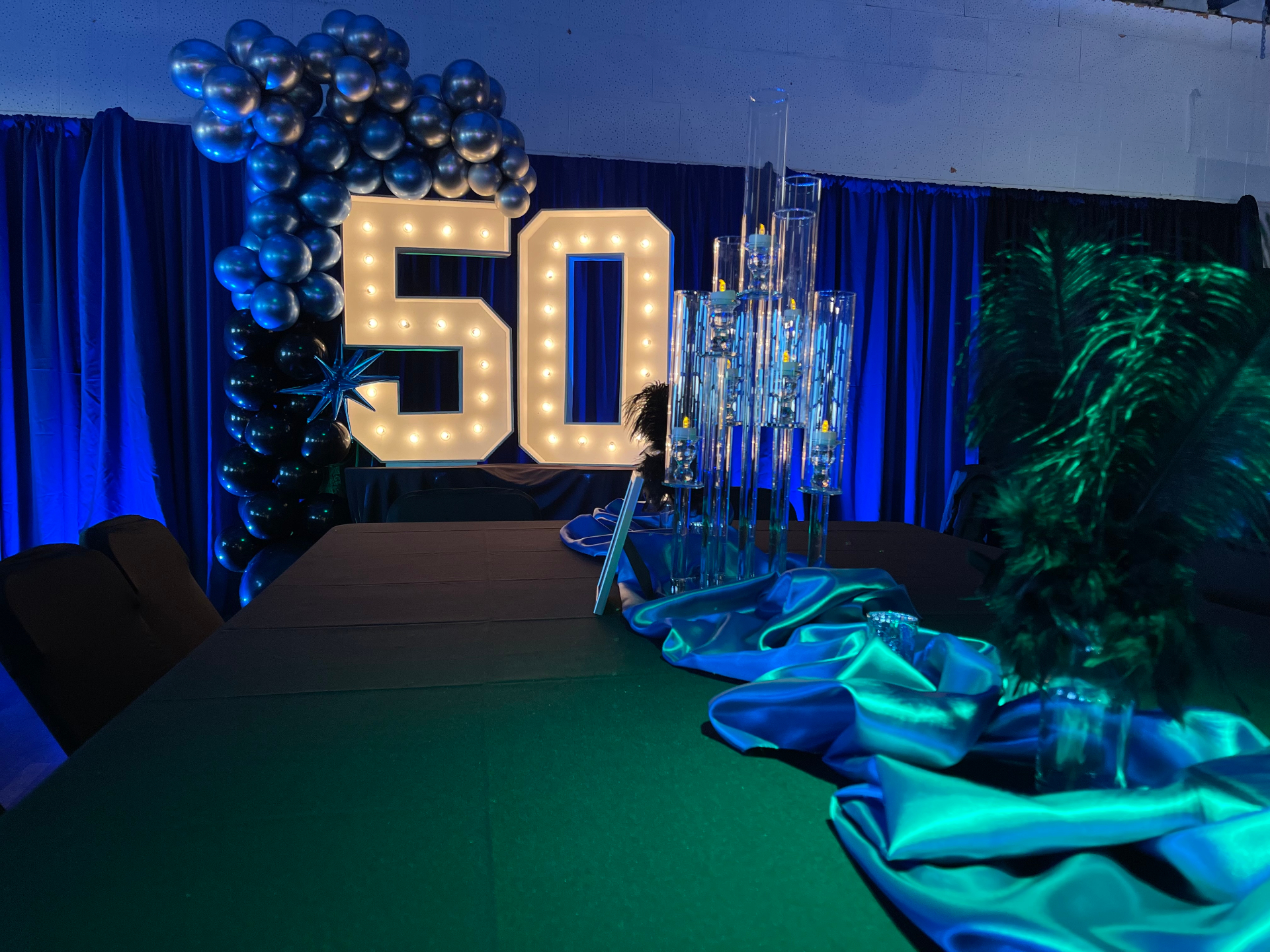 50th birthday with marquee numbers, blue drape, and tall centerpieces